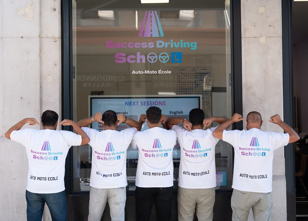 Les moniteurs Success Driving School devant l’agence de Cornavin, la salle de théorie visible derrière la vitrine