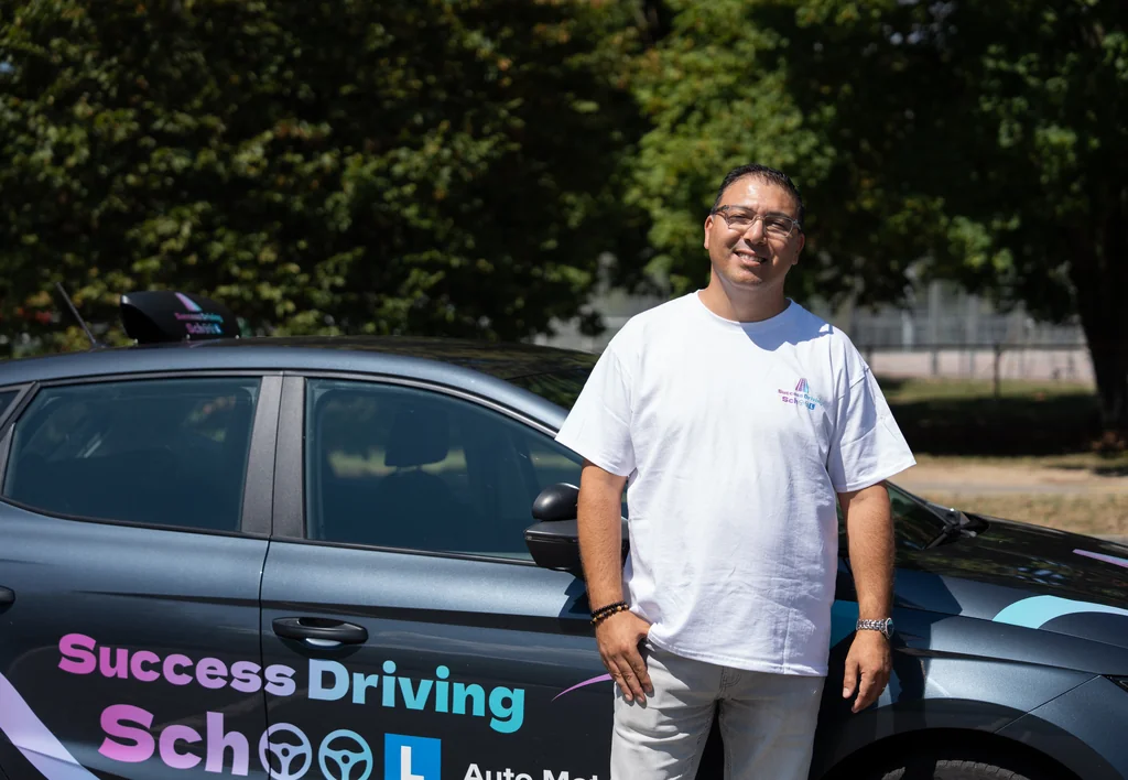 Portrait d’un moniteur Success Driving School devant une voiture aux couleurs de l’école
